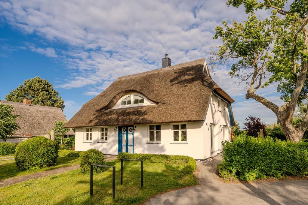 a white house with a thatched roof at Haus Tadder in Born