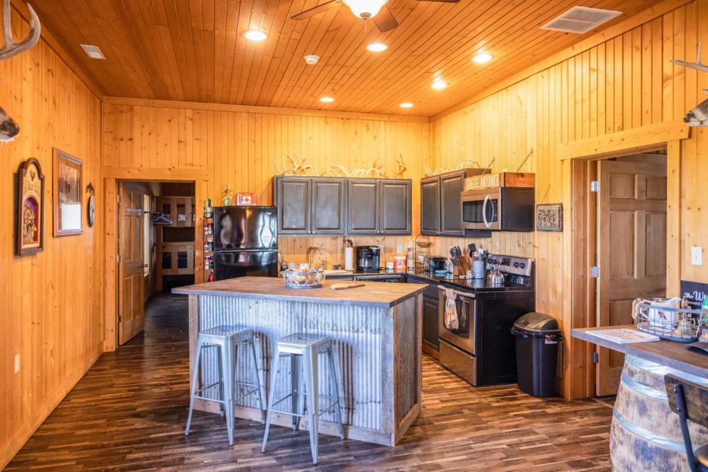 a kitchen with wooden walls and a island with bar stools at Tall Tine Lodge in La Prairie