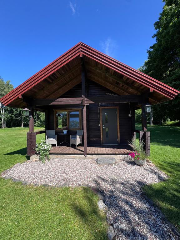 a log cabin with a red roof and a patio at Laasi Cozy Cottage in Kaigutsi