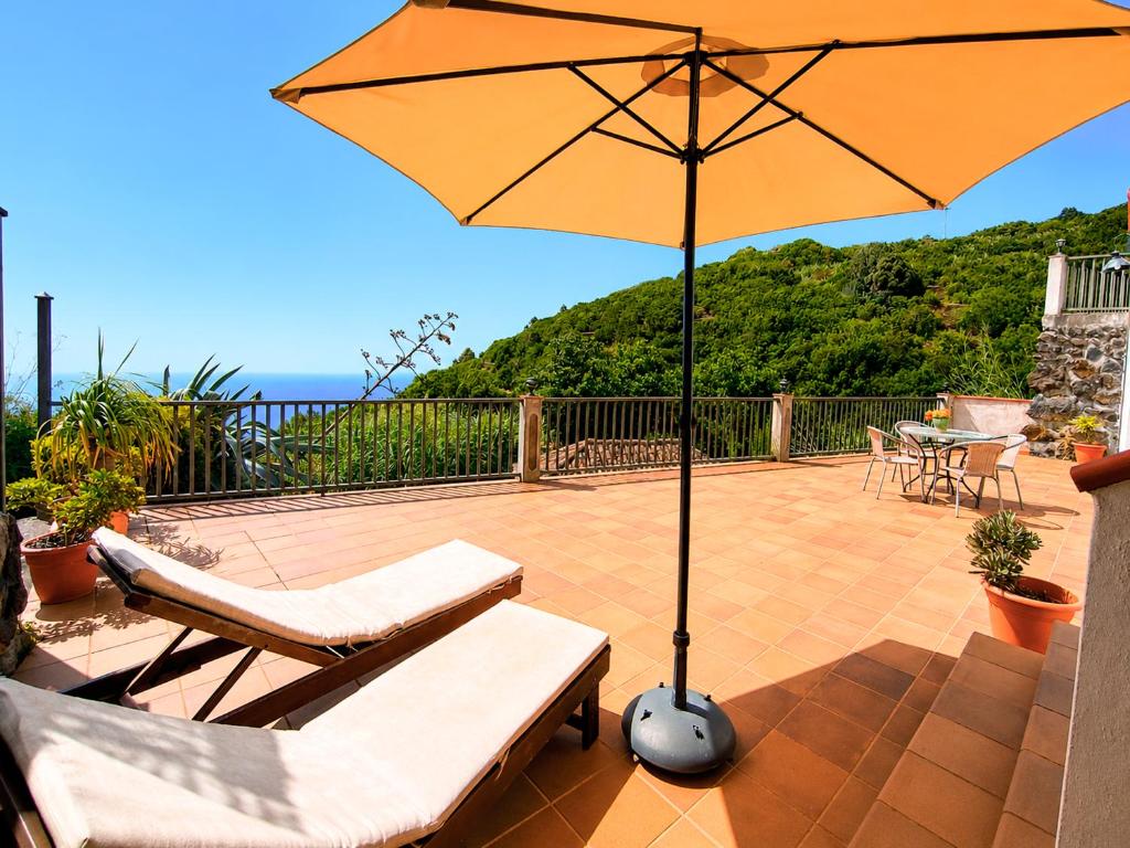 a patio with an umbrella and two chairs and a table at Neólida in Puntallana