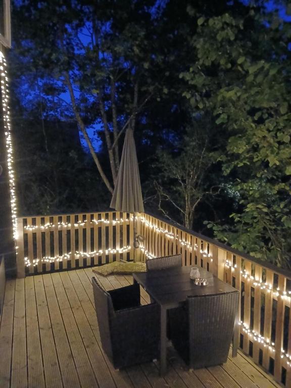 a deck with a table and chairs and lights at Bois d' Hibou in Durbuy