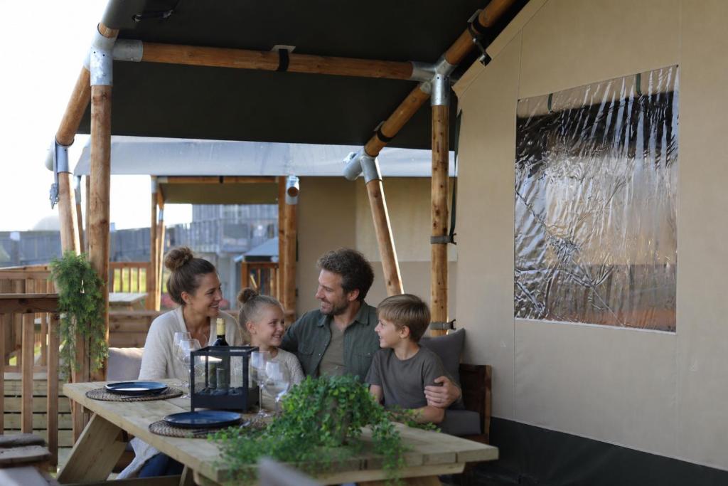 a family sitting at a table in a restaurant at Safari Lodges in Nieuwe Wetering