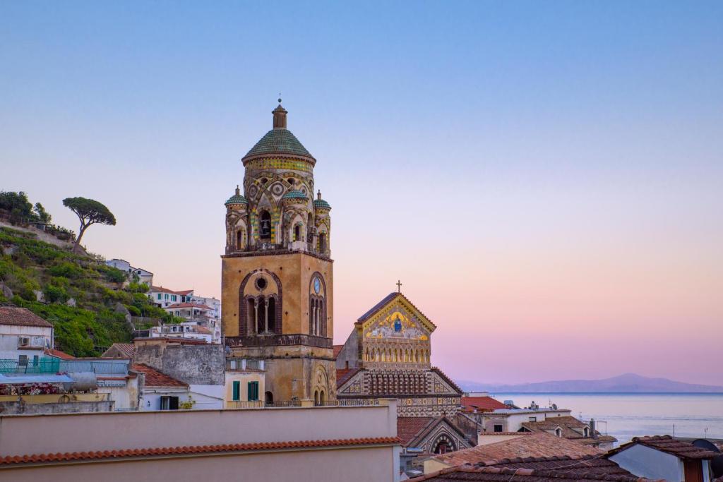 a building with a clock tower on top of a city at Amalfi Hotel centro storico in Amalfi