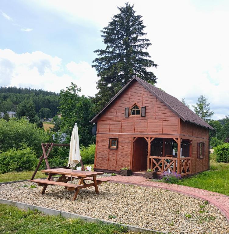 a red barn with a picnic table and a umbrella at Domek nad Potokiem in Szczytna