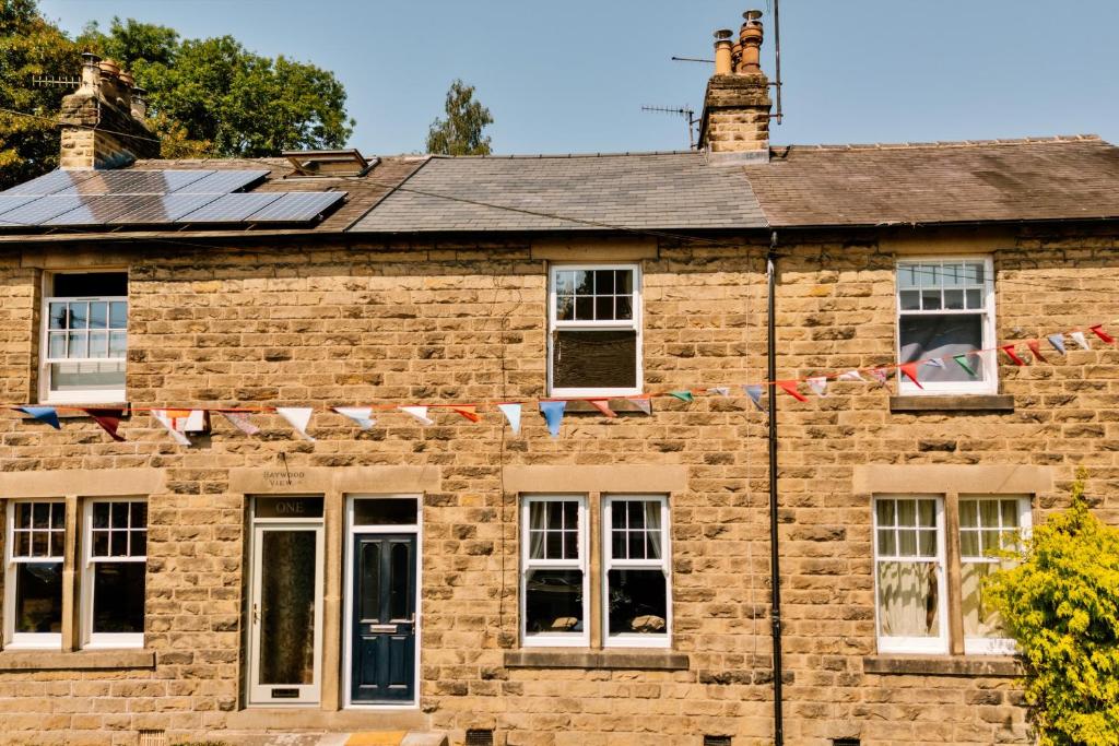 an old brick house with windows and flags on it at Finest Retreats - 2 Haywood View in Grindleford Bridge