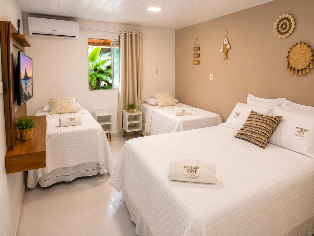 a bedroom with two beds with white sheets at Pousada da Gih in Fernando de Noronha