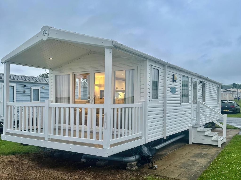 a white tiny house with a large porch at Craig Tara Holiday Park 101 Bay View in Ayr
