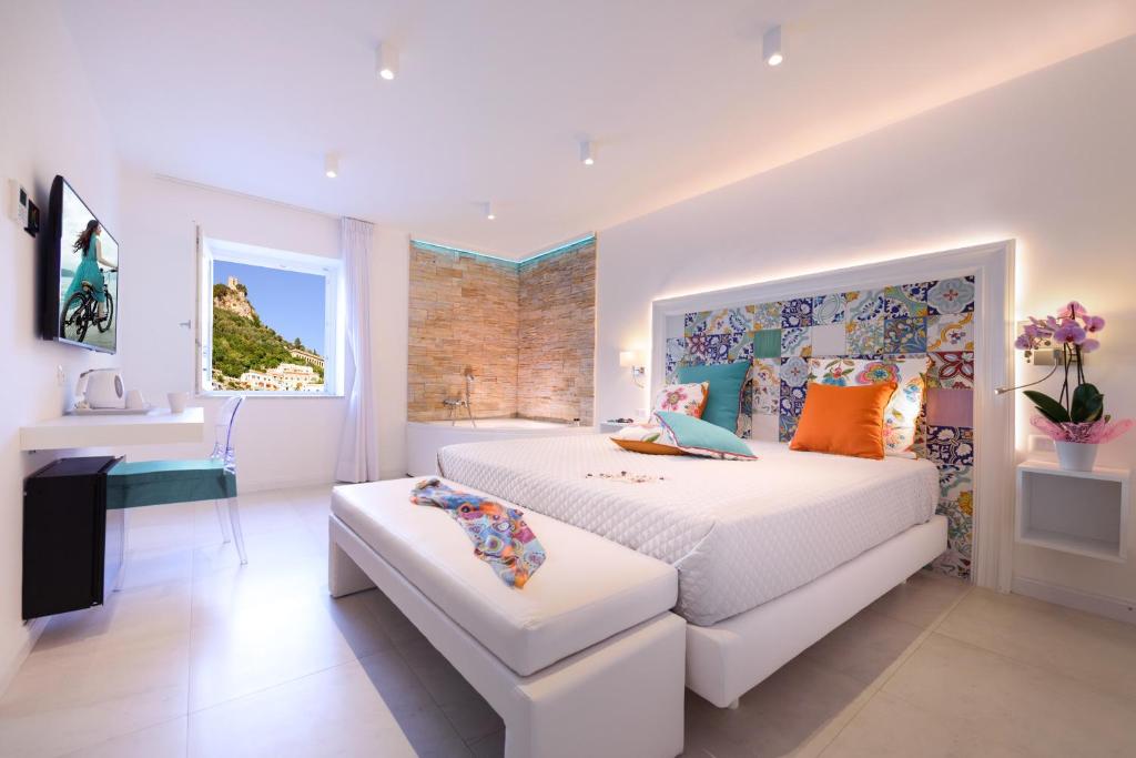 a white bedroom with a large bed and a window at Amalfi Suite Boutique Hotel in Amalfi
