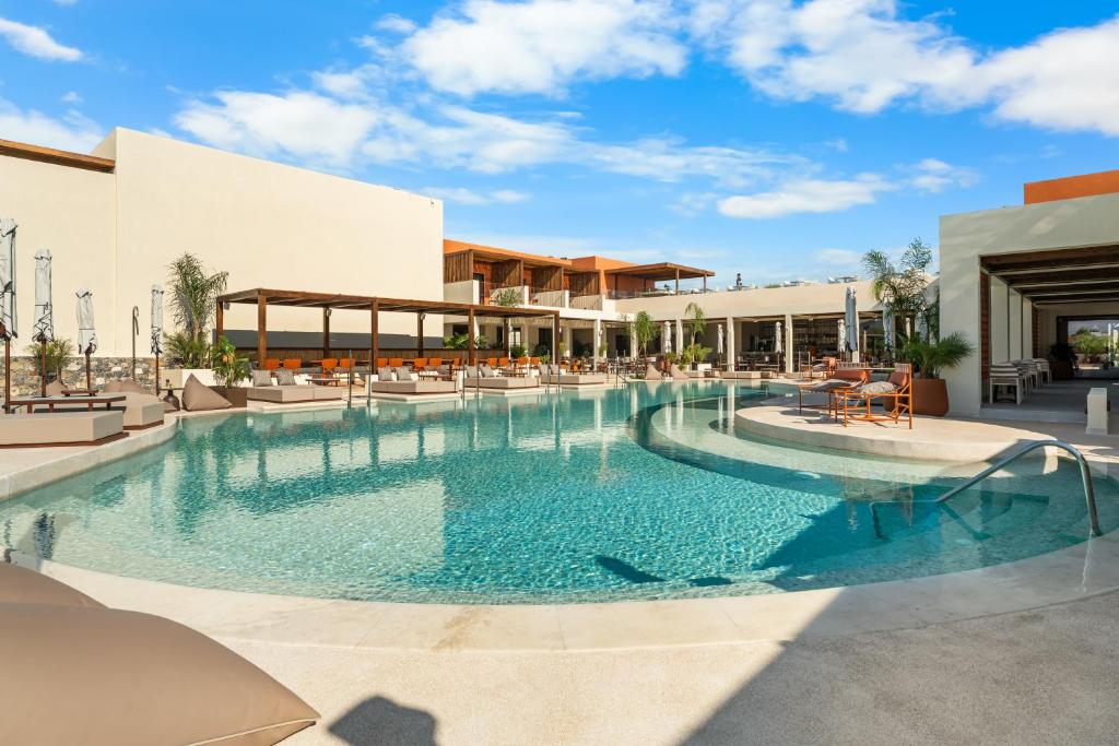 a pool at a resort with chairs and tables at ARATO by E-GEO, Adults Only in Kos