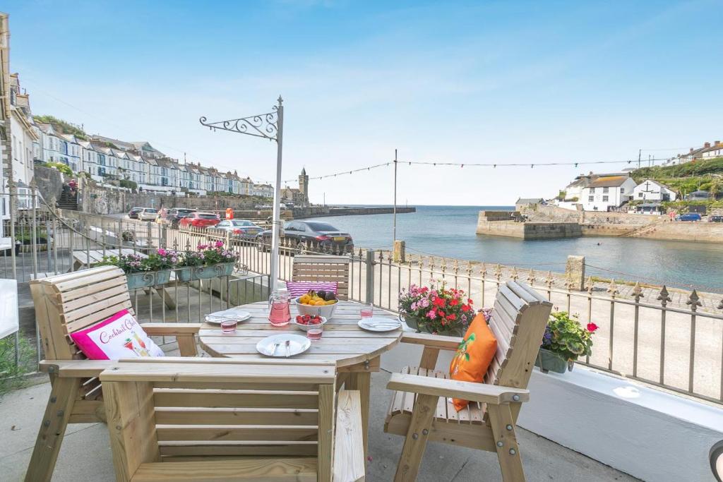 a wooden table and chairs on a balcony overlooking the water at 3 Bed in Porthleven oc-1seav in Porthleven