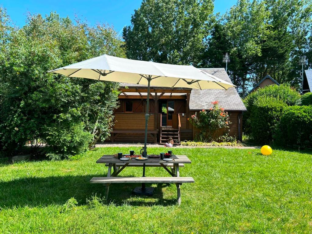 a picnic table with an umbrella in a yard at Kat in Cabourg