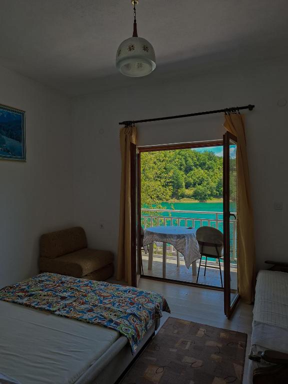 a bedroom with a bed and a balcony with a view at Camping 999 Jablaničko jezero in Železnička Stanica Ostrožac