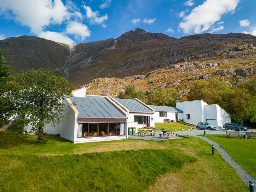 a white house with mountains in the background at Torridon Youth Hostel in Torridon