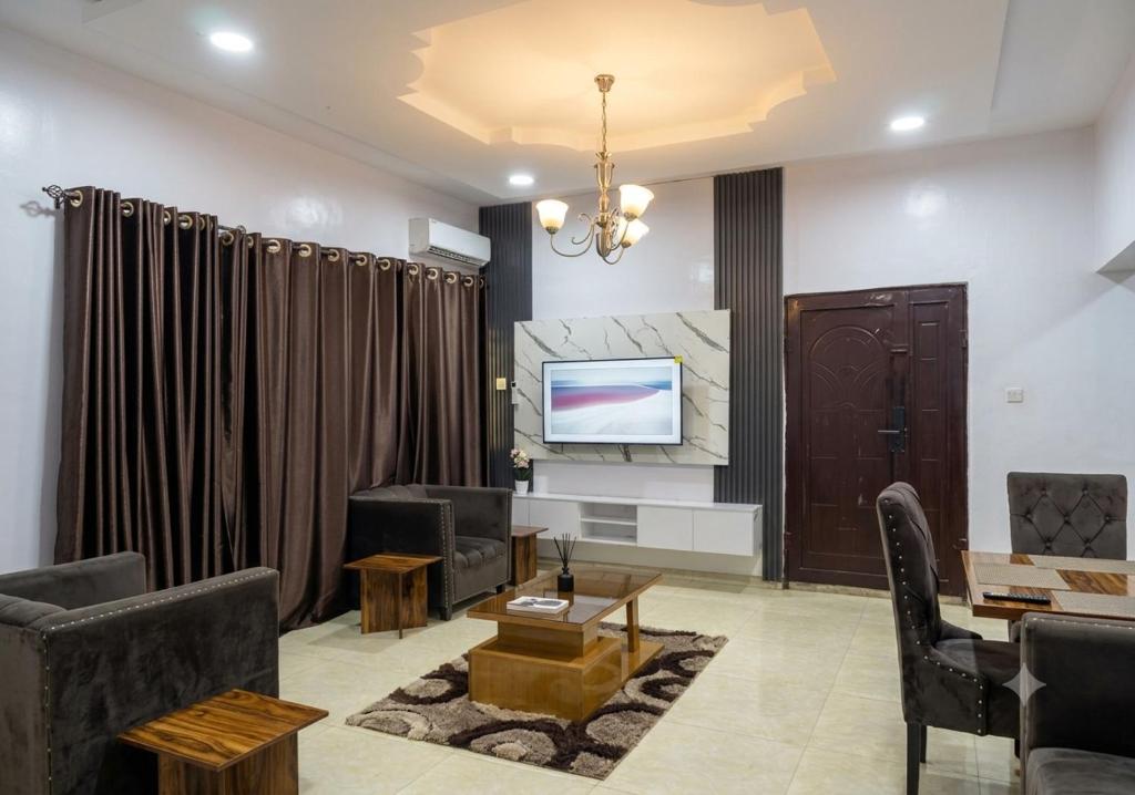a living room with a couch and a tv at Elected Apartments in Iseri-Oke
