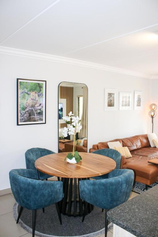 a living room with a table and blue chairs at White Orchid Luxury Apartment in Chartwell