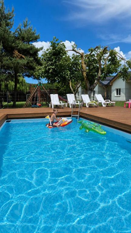 a man laying on a raft in a swimming pool at Malownicza Dolina in Wapnica
