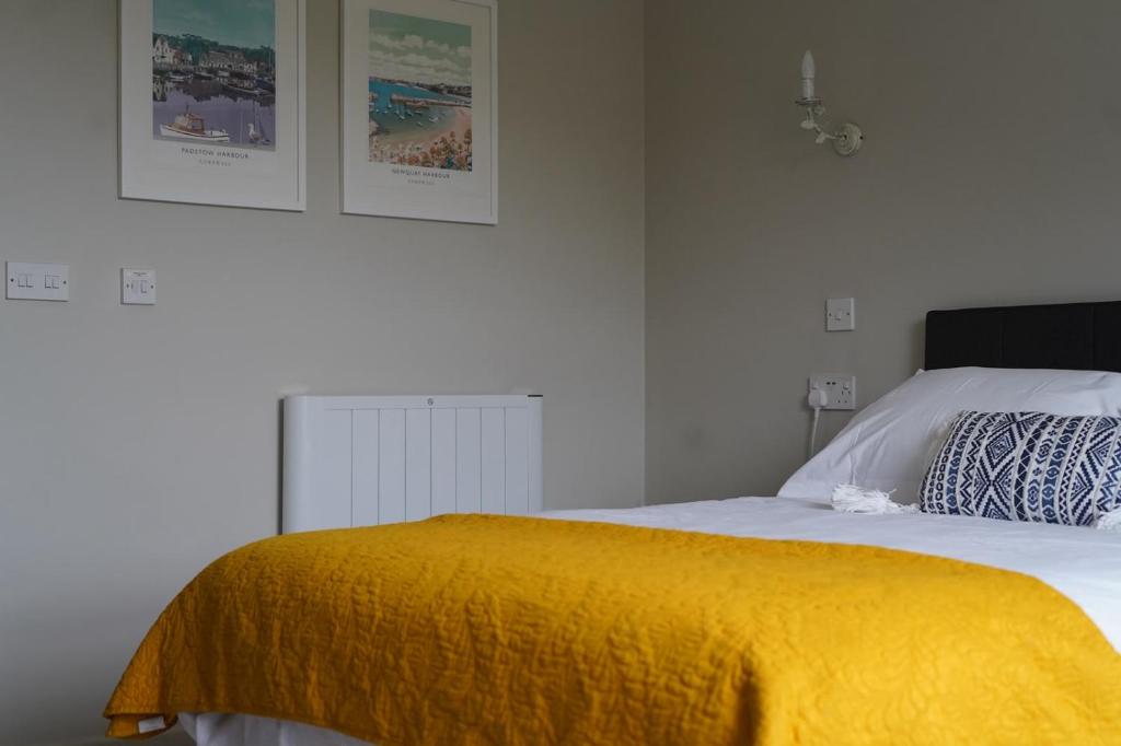 a bedroom with a bed with a yellow blanket on it at Meadows Hotel in Perranzabuloe