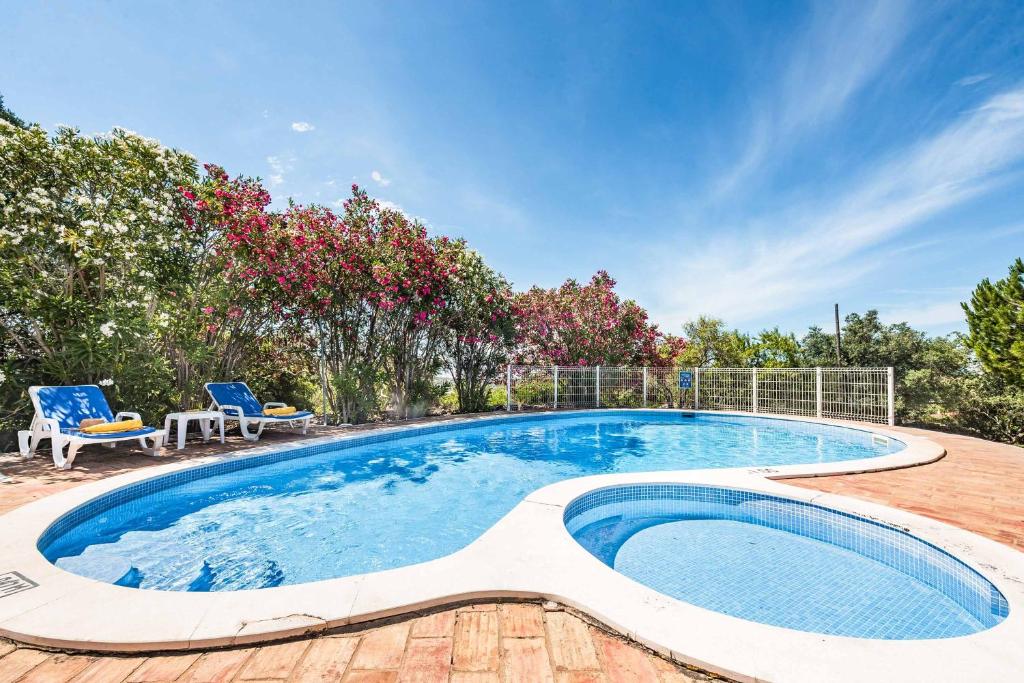a large swimming pool with two chairs and a table at Casa Nomanico in Estói