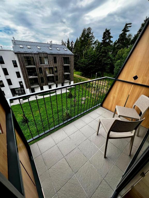 a balcony with a table and a chair and a building at Luxury Gerlach Mountain Mezonet I in Svätý Jur