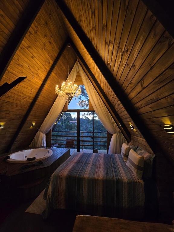 a bedroom with a bed and a tub in a room at Chalé Cristal Capivari in Campos do Jordão