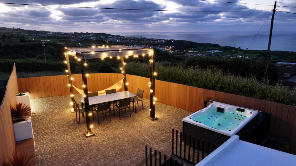 a patio with a table and lights and a hot tub at Vento do Nordeste - Cottage with Jacuzzi in Nordeste