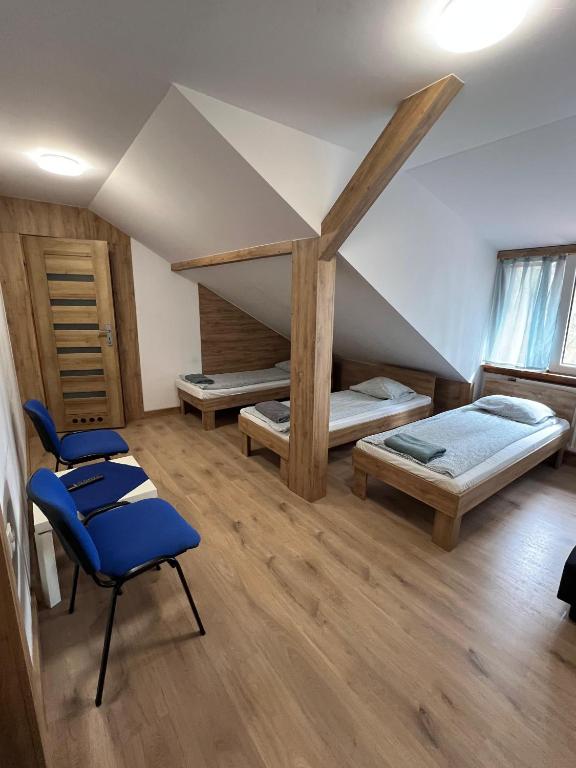 a attic room with two beds and a chair at Rezydencja pod Gwiazdami in Legarda