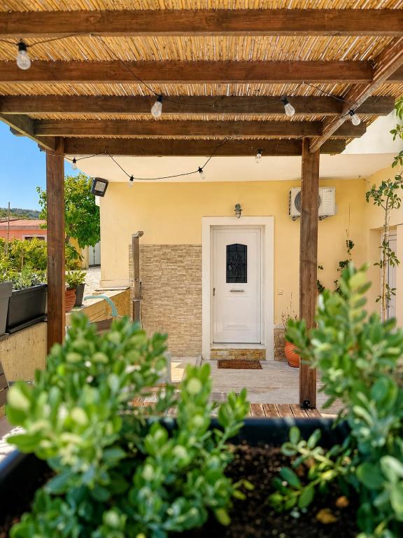 a patio with a wooden pergola and a white door at Seaside Serenity Kefalos in Kefalos