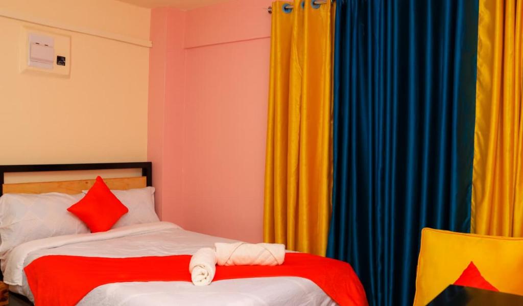a bedroom with two beds with red and blue curtains at Magik Haven Studios Nyeri in Nyeri