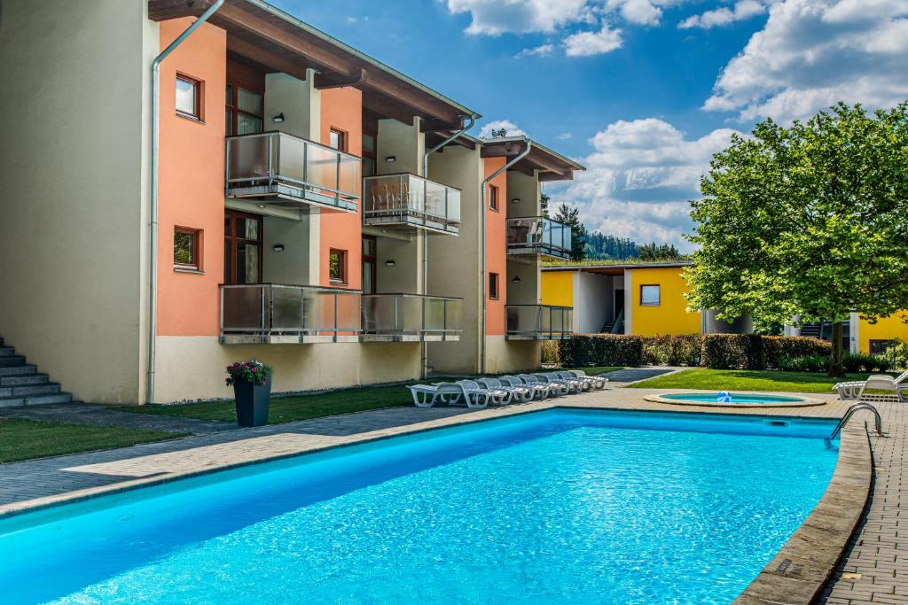 a villa with a swimming pool in front of a building at Velvet Lipno in Lipno nad Vltavou