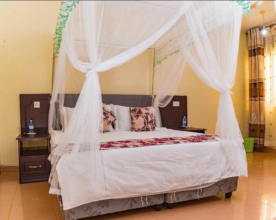 a bedroom with a canopy bed with white drapes at Ebenezer resort hotel in Mbale