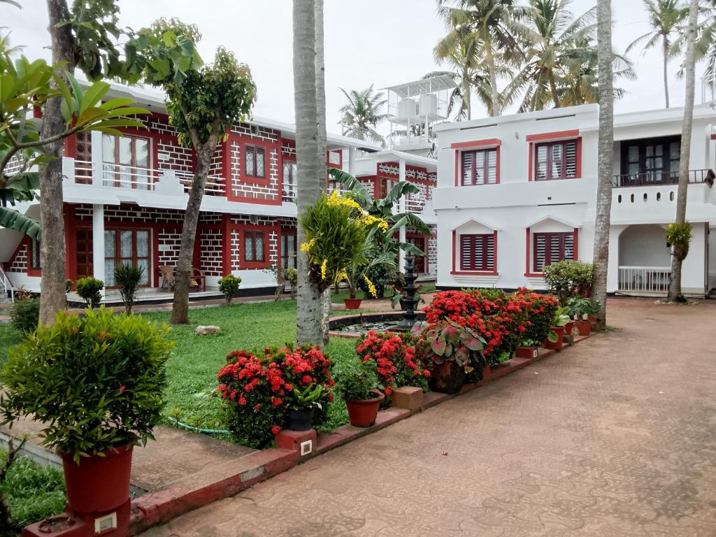a courtyard of a red and white building with potted plants at Hillview Beach Resort in Varkala