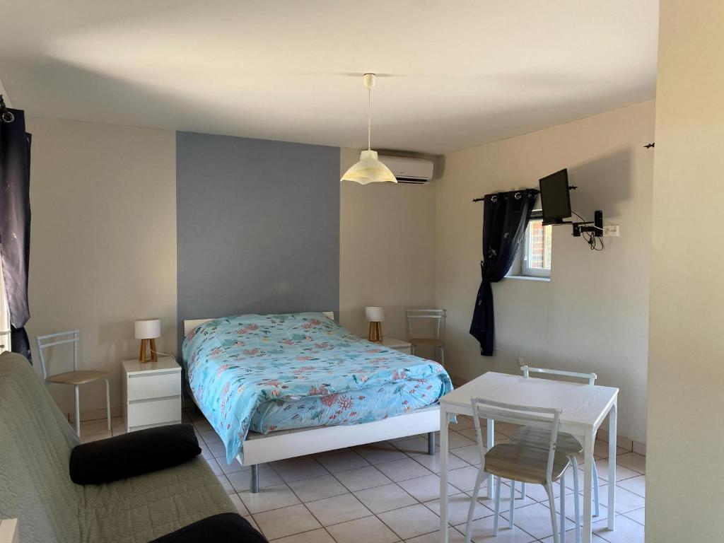 a bedroom with a bed and a table and a chair at Meublé BLEU in Réaumur