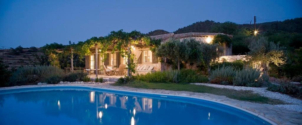 a home with a swimming pool in front of a house at Aphrodite's Oasis in Pomos