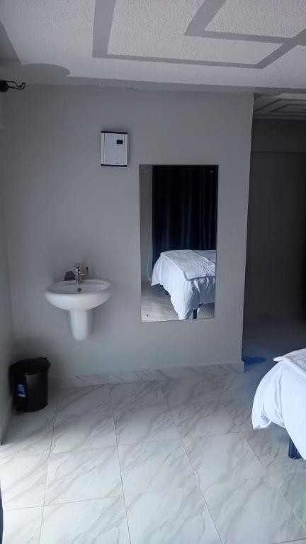 a white room with a sink and a bed at Rimayalounge in Embu