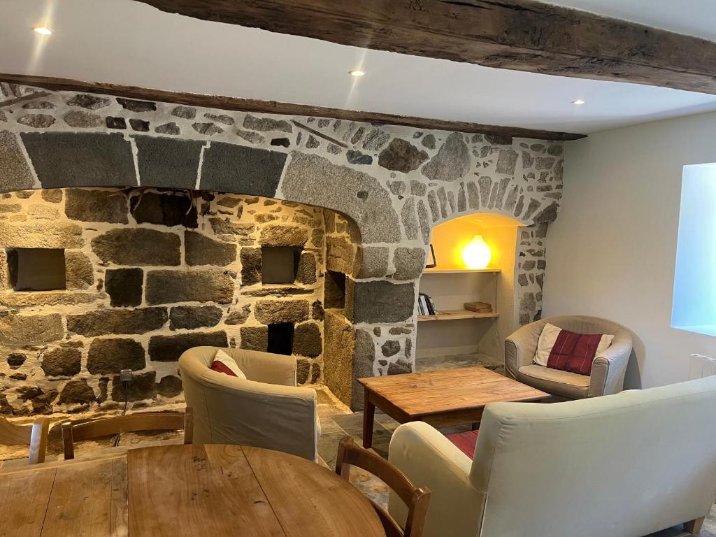 a room with a stone wall with a table and chairs at Gîte du Redondet in Cisternes-la-Forêt