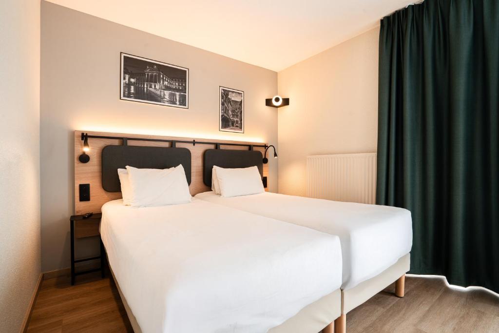 a bedroom with a white bed and a green curtain at Campanile PRIME - Dijon Centre Gare in Dijon
