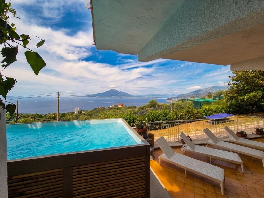 a pool with chairs and a view of the ocean at Villa Blu Sorrento seaview pool terrace and Jacuzzi in Sorrento