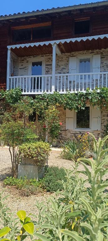 an old house with a white porch and plants at Le Balcon Commingeois in Chein-Dessus
