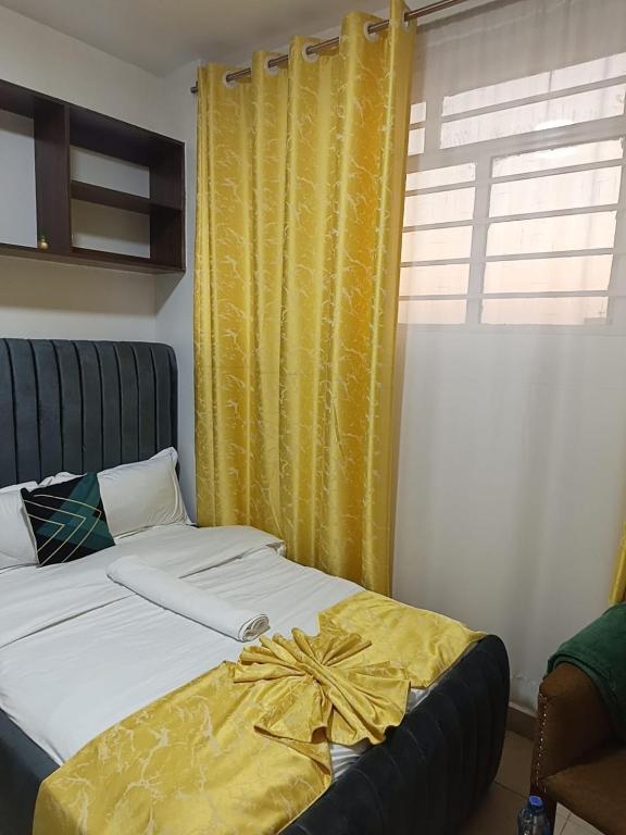 a bedroom with a bed with a yellow curtain at Gweth Haven Homes in Nakuru