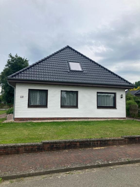 a white house with a black roof at Haus Eichholz in Tellingstedt