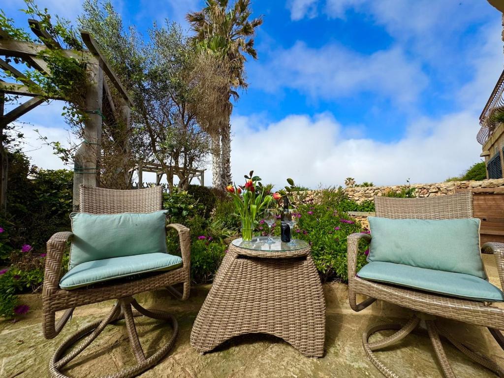 a patio with two chairs and a table with at Tranquil garden hideaway in Gozo in San Lawrenz