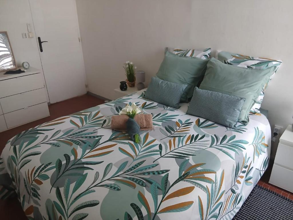 ein Schlafzimmer mit einem Bett mit einer geblümten Tagesdecke in der Unterkunft le Petit Cocon ! in Pointe-à-Pitre