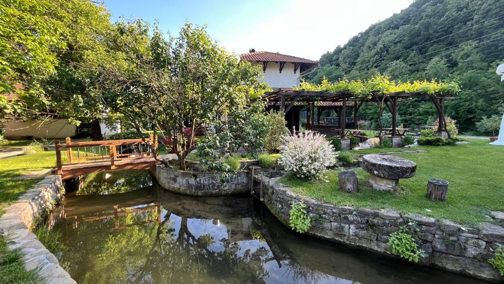 a garden with a pond and a gazebo at Vodenica kod Uče in Gukoš