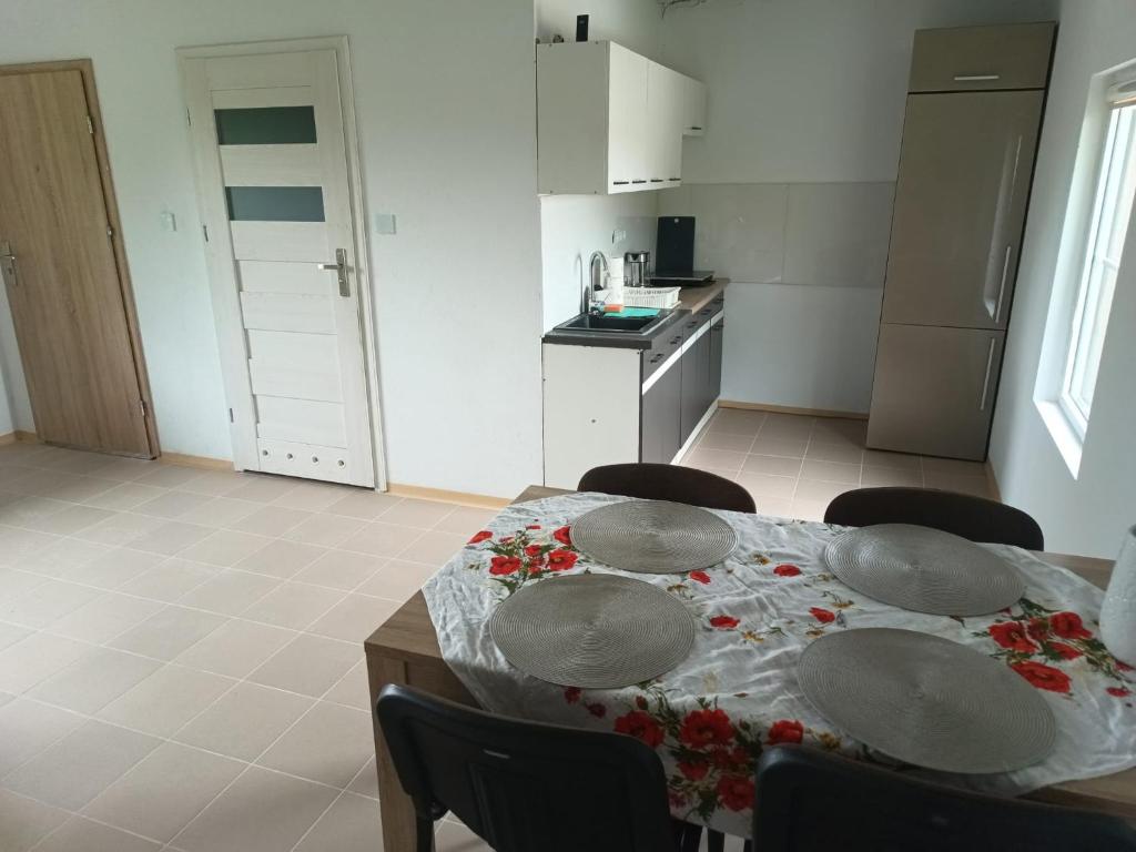 a kitchen with a table with chairs and a tablecloth on it at Śródziemie Erebor in Leśno