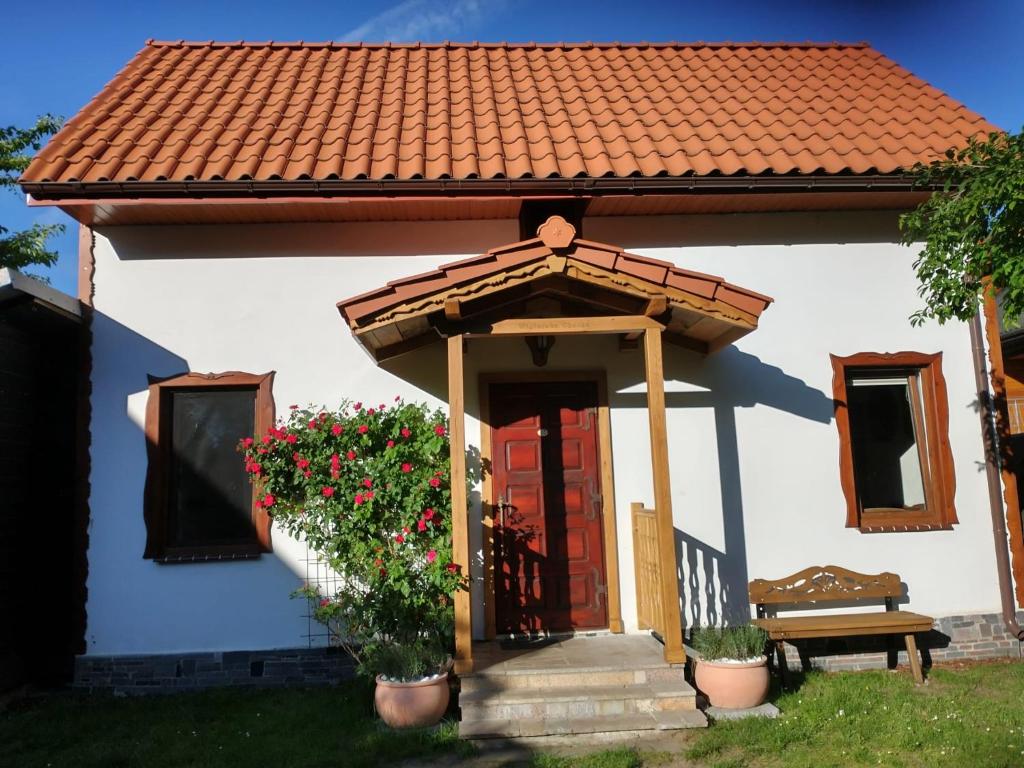 a small house with a red door and flowers at Wigierska Chatka in Gawrych Ruda