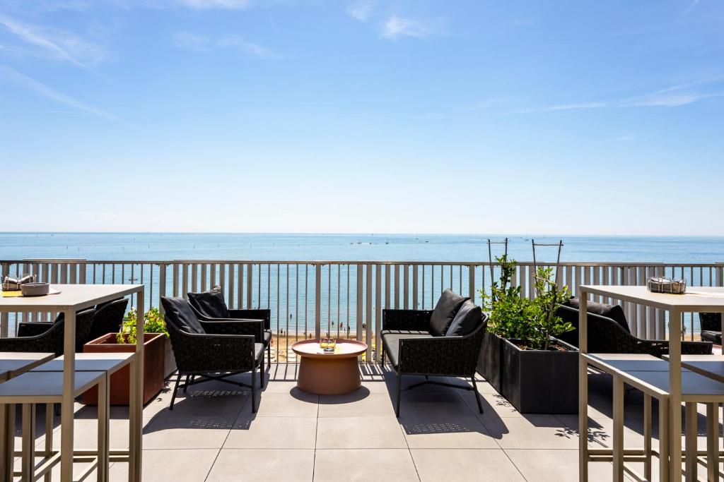 a patio with tables and chairs and the ocean at DIVA HOTEL LIGNANO - Adults Only in Lignano Sabbiadoro