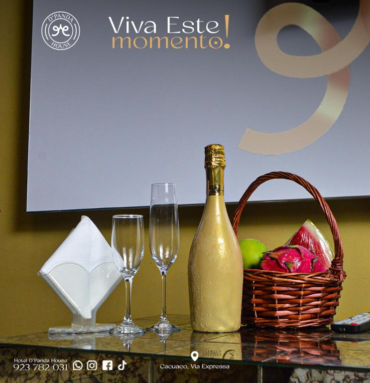 a bottle of champagne and a basket of fruit and wine glasses at Hotel DPanda House in Cacuaco