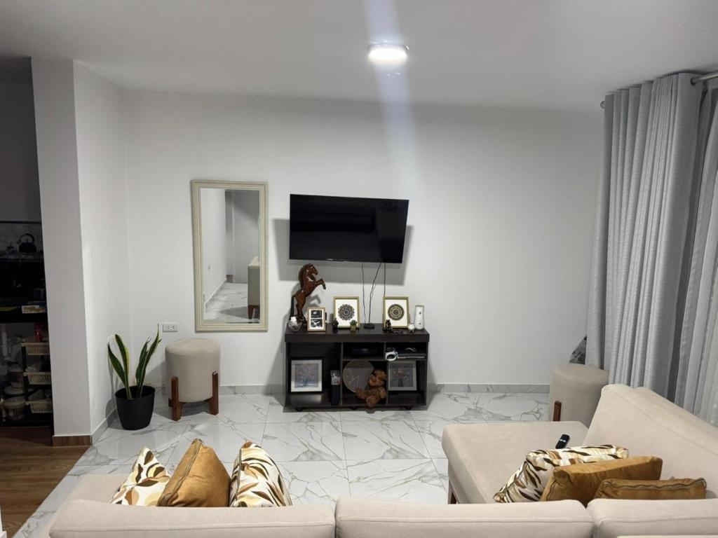 a living room with two white couches and a mirror at Depa Ángel in Moyobamba
