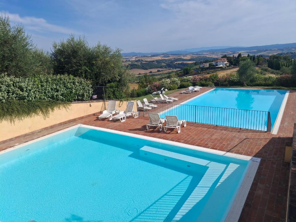 a large swimming pool with lounge chairs at Garbo Home in Asciano
