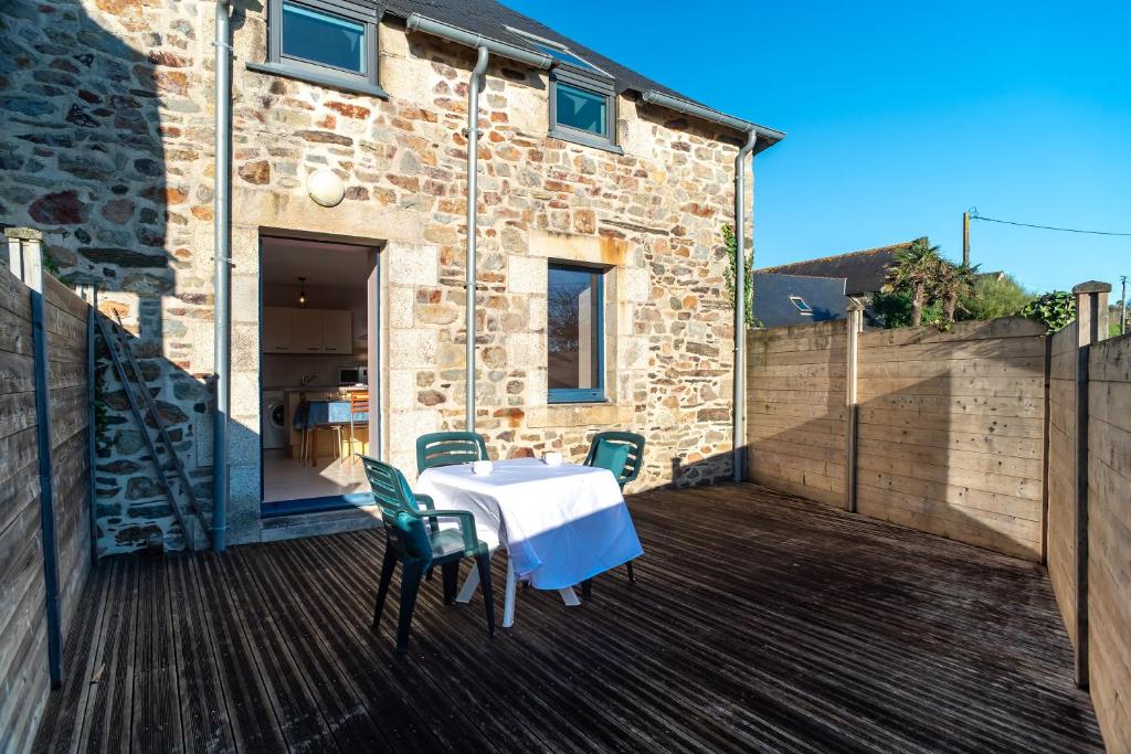 a patio with a table and chairs on a deck at Les Chouettes - Au Soleil Breton in Saint-Nic